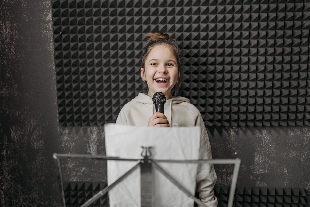 Home Young girl singing into a microphone during a music lesson in a studio.